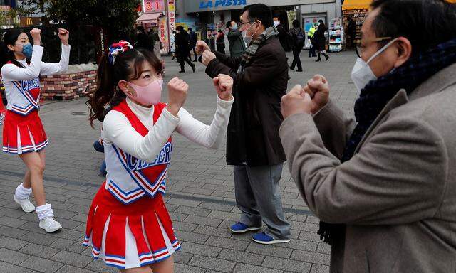 Cheerleader versuchen in Tokio während der Pandemie Passanten aufzuheitern.