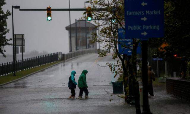 Menschen stapfen auf einer überschwemmten Straße in der Stadt New Bern im US-Bundesstaat North Carolina.