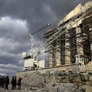 Tourists look at the temple of Parthenon atop the Acropolis hill in Athens