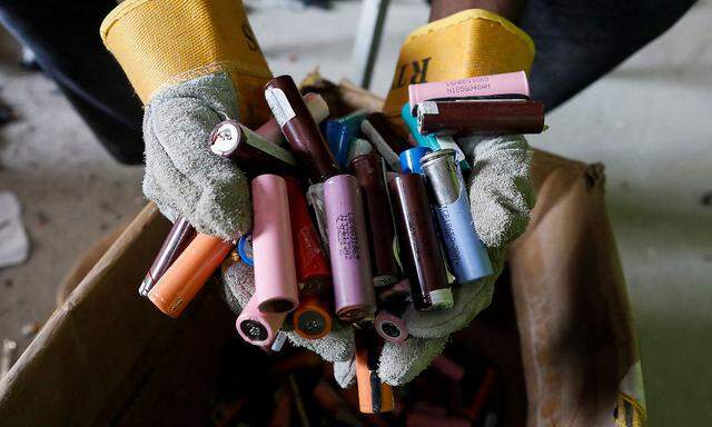 An employee holds a handful of  lithium-ion cells from old laptop battery packs at the Quadloop recycling facility in Lagos