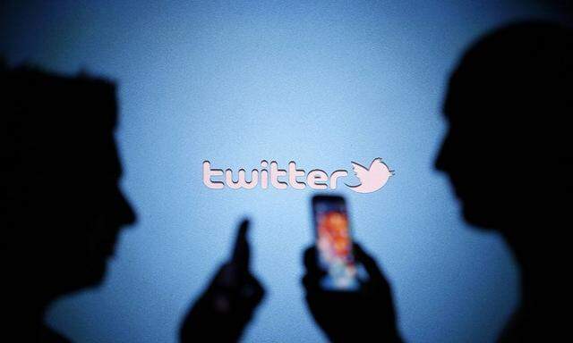 Men are silhouetted against a video screen with a Twitter logo as they pose with Samsung S3 and S4 smartphones in this photo illustration taken in the central Bosnian town of Zenica in this file photo