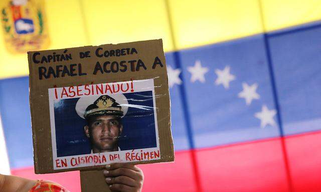 A woman shows a placard with a picture of Rafael Acosta, after a news conference in Caracas