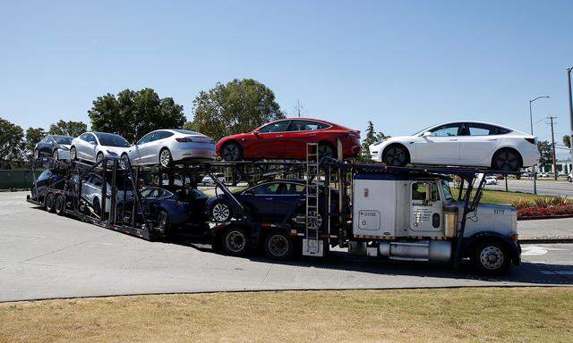 A car carrier trailer carries Tesla Model 3 electric sedans, is seen outside the Tesla factory in Fremont