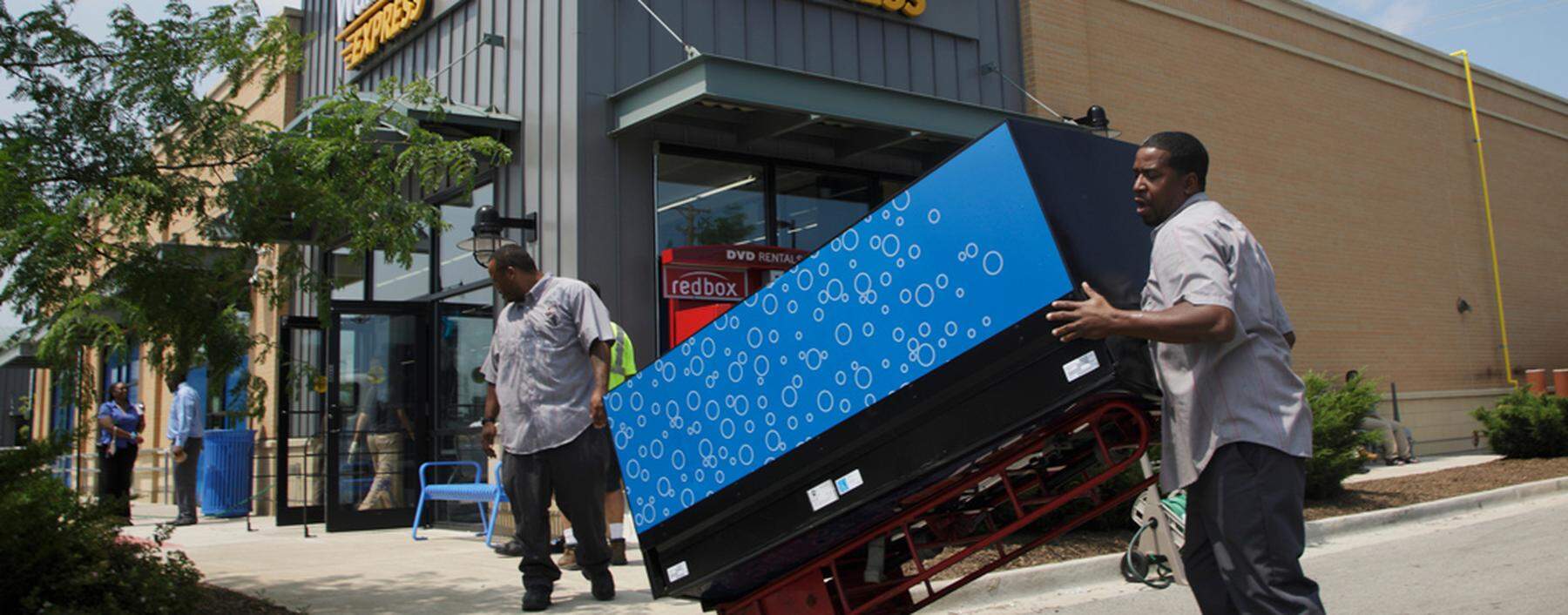 Workers move a vending machine into position outside a new Walmart Express store in Chicago