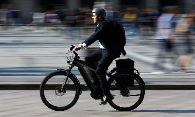 A man rides an electric bicycle, also known as an e-bike, in downtown Milan