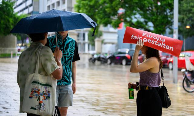 Schutzsuche vor dem Regen unter einer SPÖ-EU-Tafel 