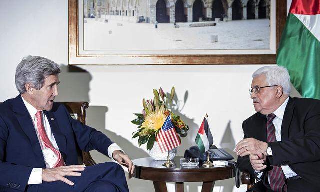 U.S. Secretary of State John Kerry and Palestinian president Mahmoud Abbas talk before a meeting at the presidential compound in the West Bank city of Ramallah