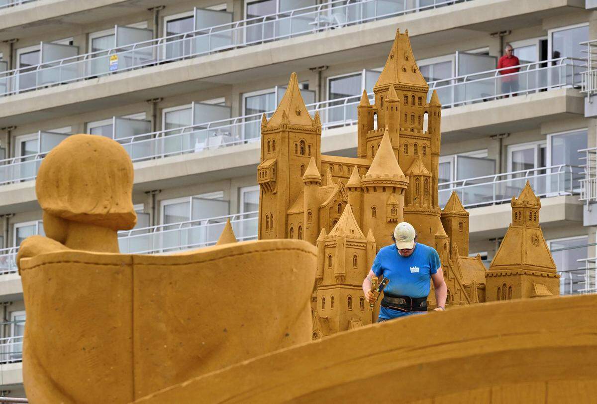 22. Juni. Vor Beginn des Sandskulpturenfestivals im belgischen Middelkerke arbeitet ein Künstler an einer Skulptur, die Figuren aus Märchen darstellt.