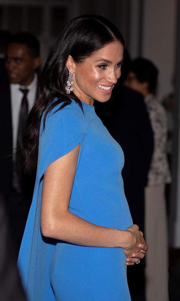 Die Hand am Bauch war wohl das auffälligste Accessoire an diesem Abend: Für ein Staatsbankett zog sich Herzogin Meghan noch einmal um und bezauberte in einem „Fidschi“-blauen (der Farbton soll das Blau in der Fahne des Inselstaates widerspiegeln) Cape-Kleid des Labels Safiyaa die Gäste - und mit ihrem schon recht deutlich sichtbaren Babybauch.