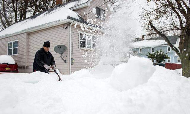 Ron Jeblonski uses a snow blower to clear snow from his driveway in South Buffalo