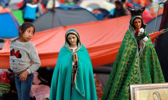 A child stand next to an image of the Virgin of Guadalupe at the Basilica of Guadalupe during the annual pilgrimage in honor of the Virgin of Guadalupe, patron saint of Mexican Catholics, Mexico City