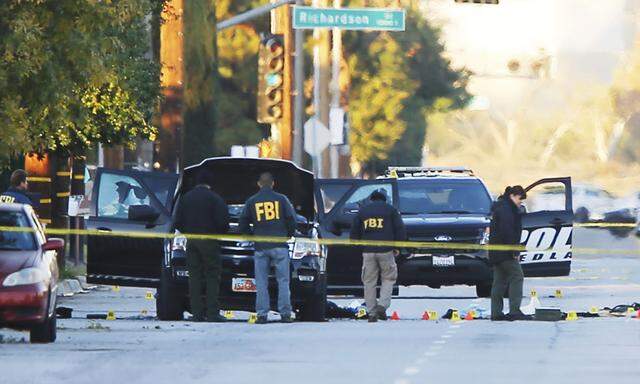 FBI and police investigator are seen around a vehicle in which two suspects were shot following a mass shooting in San Bernardino California