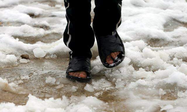 A Syrian youth Khaled from Raqqa walks on snow wearing slippers in the Bekaa Valley refugee camp in Lebanon after the first heavy snow storm hit Lebanon