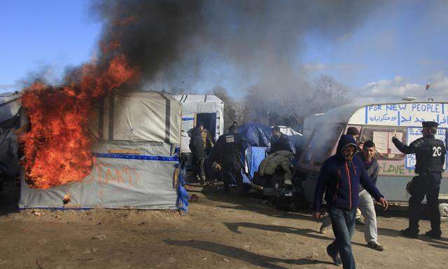 Smoke and flames rise from a burning makeshift shelter during the partial dismantlement of the camp for migrants called the ´jungle´, in Calais