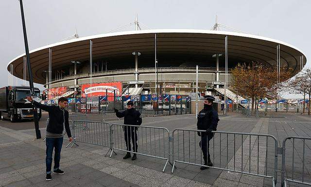 Archivbild: polizisten und ein Passant am Tag nach den Anschlägen vor dem Stade de France