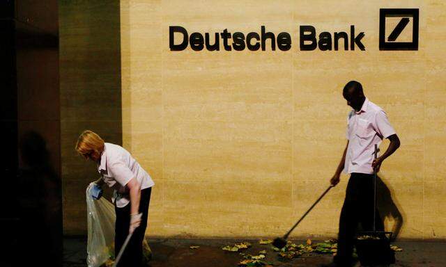 Workers sweep leaves outside Deutsche Bank offices in London