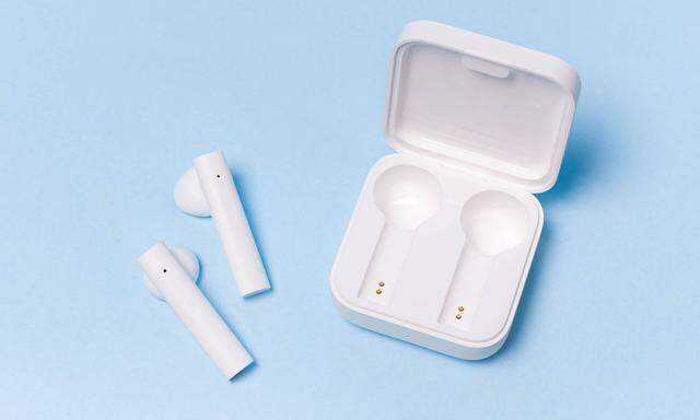 Wireless white headphones on a plain background . White headphones. Solid color background. Modern electronics. Future t