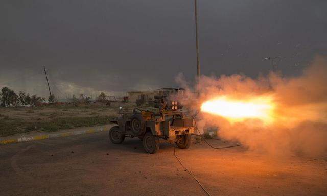 Shi'ite fighters fire a rocket during clashes with Islamic State militants in Salahuddin province