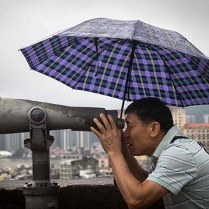A visitor uses binoculars look at the Macau skyline from Monte Fort during the Labour Day holiday in Macau on May 1, 2024. (Photo by Eduardo Leal / AFP)
