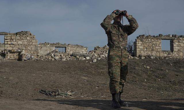 FILE PHOTO: An ethnic Armenian soldier looks through binoculars as he stands at fighting positions near divided Taghavard village in Nagorno-Karabakh region