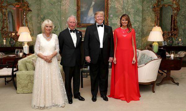 „Bitte lächeln“: Prinz Charles und Herzogin Camilla sind an diesem Abend im Auftrag Ihrer Majestät unterwegs und stellen sich für das obligatorische Gruppenfoto mit dem Präsidentenehepaar vor historische Tapete. Während sich Melania dieses Mal in Knallfarbe nicht zurückhält, passt sich Camilla farblich ihrer Umgebung (Möbel, Lampen, Teppich) an. So sieht es also aus, wenn königliche Eleganz auf präsidialen Pomp trifft.