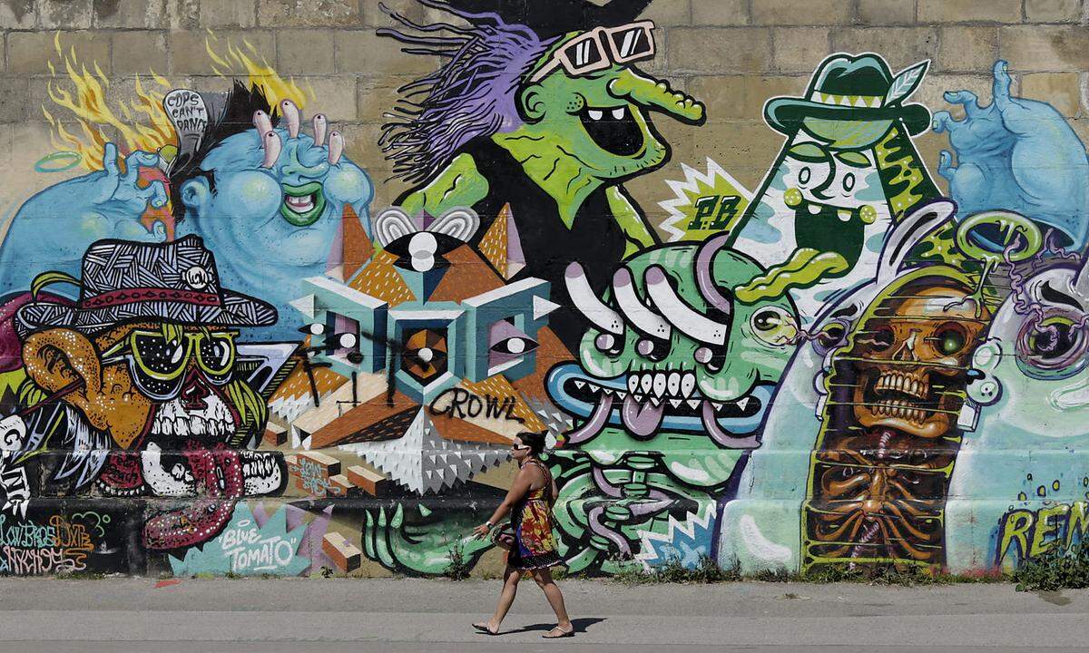 A woman passes a graffiti on a hot summer day in Vienna