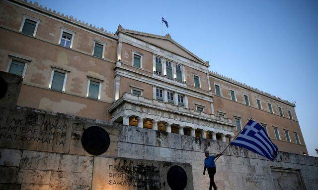 FILE PHOTO: A man waves a Greek flag during an anti-goverment rally outside the Greek parliament building in Athens