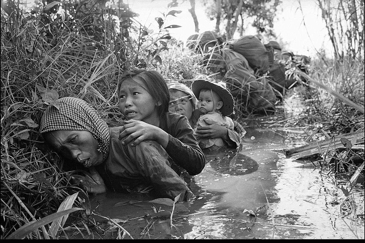 Vietnam, Jänner 1966, Bao Trai, 20 Meilen westlich von Saigon: Frauen und Kinder verstecken sich vor einem Feuergefecht der US-Soldaten mit dem Vietkong in einem Kanal.