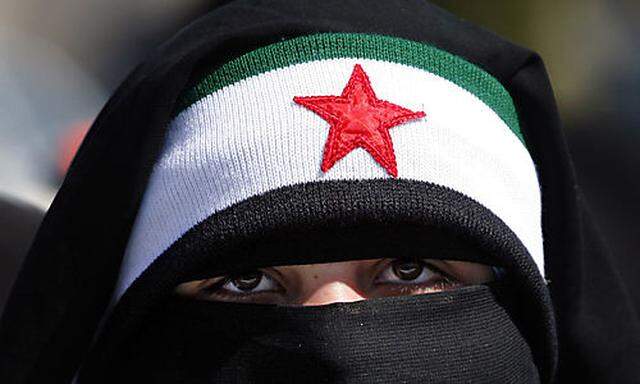 A veiled Syrian woman wears the colors of the revolutionary flag during a protest in front the Syrian