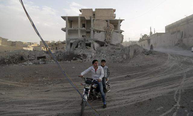Residents ride a motorcycle in a site damaged by what activists said were airstrikes carried out by the Russian air force in the rebel-controlled area of Maaret al-Numan town in Idlib province, Syria