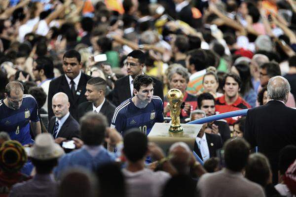 Bao Tailiang, China, Chengdu Economic DailyDer argentinische Fußball-Star Lionel Messi erspäht einen Blick auf den Weltmeisterschaftspokal kurz nachdem sein Team das Finale gegen Deutschland verloren hatte.