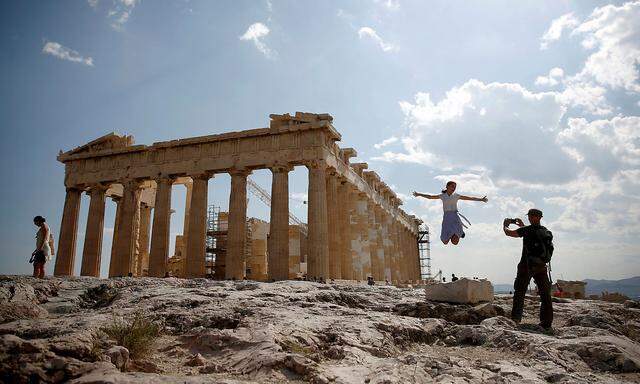 Tourists take a picture in front of the temple of the Parthenon atop the Acropolis in Athens