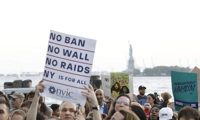 People hold placards during a protest against U.S. President Donald Trump's immigration policies in New York City