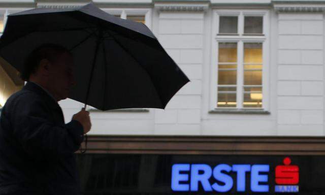 A man with an umbrella passes the entrance of the headquarters of Austrian Erste Group Bank  in Vienna