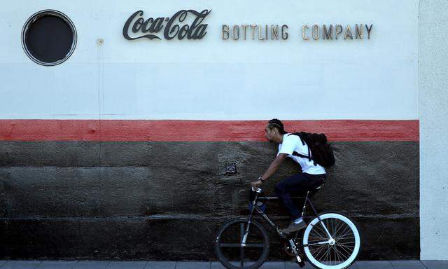 A man cycles past the Coca Cola bottling plant in Los Angeles