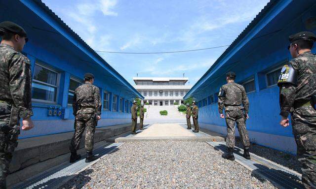 Südkoreanische (vorn) und nordkoreanische Soldaten stehen sich an der Demarkationslinie in Panmunjom gegenüber, wo Moon Jae-in und Kim Jong-un zusammenkommen.