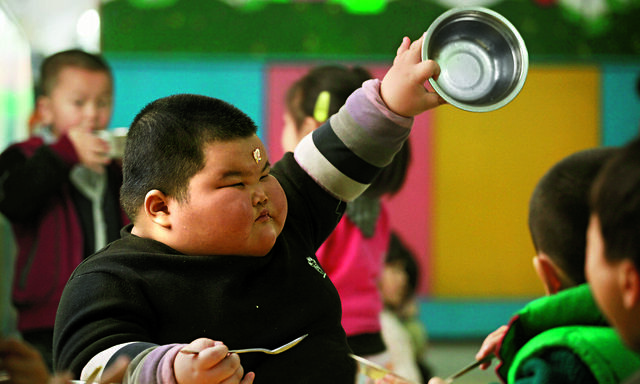 Lu Zhihao shows his empty rice bowl to his teacher during lunch time at a kindergarten in Foshan