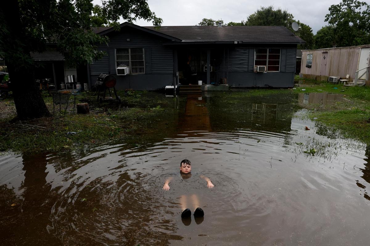 8. Juli. Ein Junge badet im überschwemmten Garten, nachdem Hurrikan „Beryl“ durch Rosenberg, Texas, gezogen ist.
