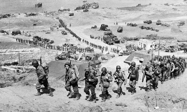 Handout photo of U.S. Army reinforcements marching up a hill past a German bunker after the D-Day landings near Colleville sur Mer