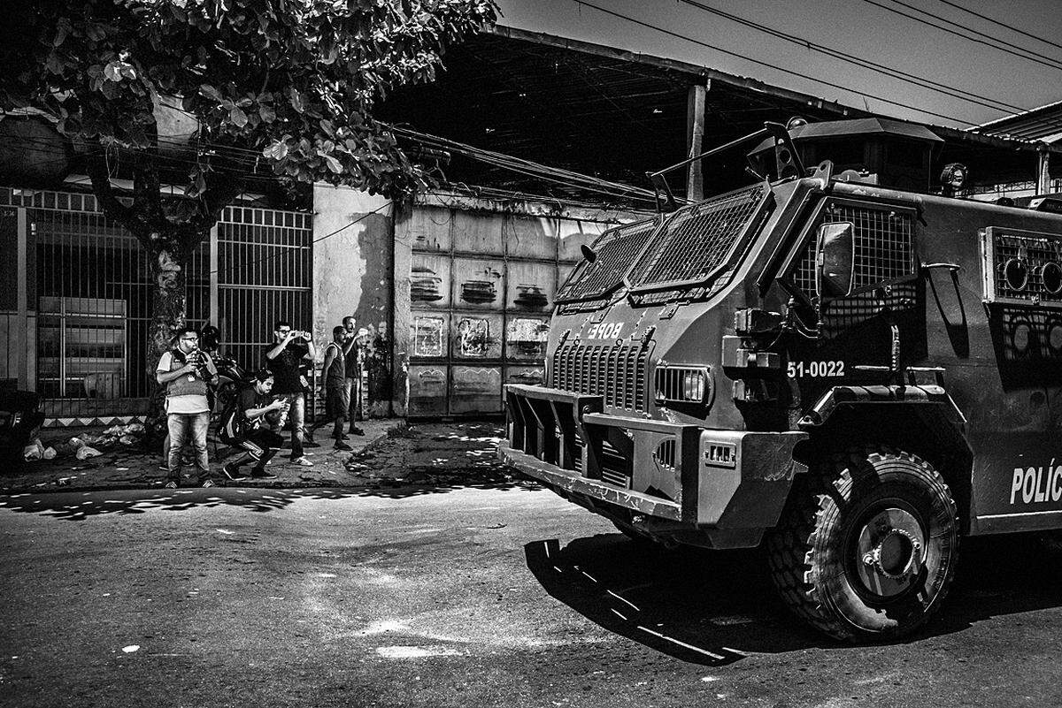 Sebastián Liste, Spanien, 2015, veröffentlicht in: Noor Aus der Serie "Citizen Journalism in Brazil's Favelas": Papo Reto ist eine Bürgerjournalismus-Iniviative. Papo Reto-Mitglieder fotografieren ein Polizei-Sondereinsatzfahrzeug auf Patrouille in den Straßen nach einer Erschießung. Erschießungen durch die Polizei in den Favelas von Rio de Janeiro kommen so häufig vor, dasssie selten gemeldet werden. Amnesty International zufolge werden jährlich rund 2000 Menschen von der brasilianischen Polizei getötet, wobei die Weise oft einer geplanten Exekution ähnelt. In Complexo do Alemão, einer der größten Favelas von Rio, haben die Anwohner, frustriert durch die fehlende Berichterstattung in den traditionellen Medien, „Papo Reto“ (ehrliche Rede) gegründet. Dieses Kollektiv sammelt und verbreitet Bilder und Meldungen über soziale Medien.
