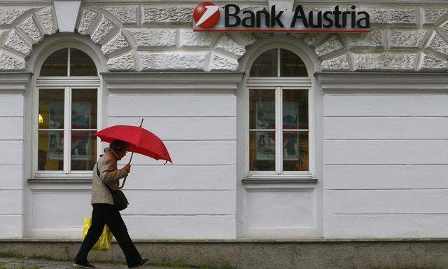 A woman carrying an umbrella passes a Bank Austria branch office in Vienna