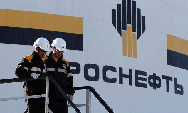 Workers stand next to logo of Russia's Rosneft oil company at central processing facility of Rosneft-owned Priobskoye oil field outside Nefteyugansk
