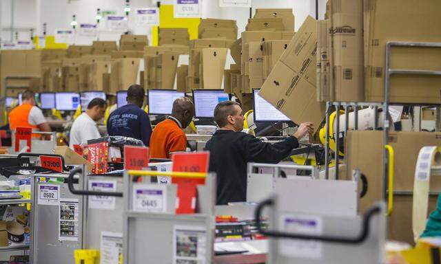 Workers pack orders at the Amazon logistics center in Brieselang