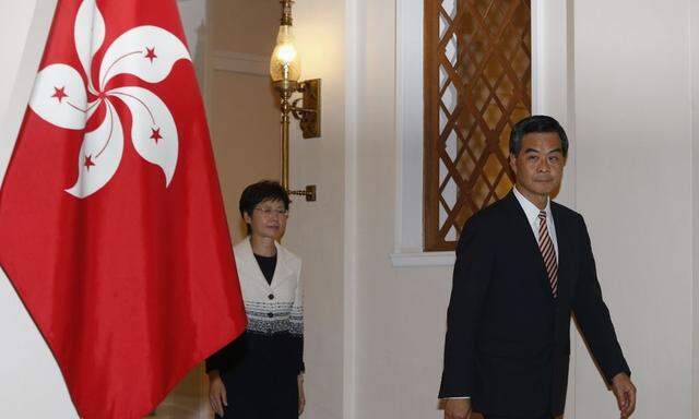 Hong Kong Chief Executive Leung Chun-ying and Chief Secretary Carrie Lam walk past a Hong Kong flag as they attend a news conference in Hong Kong