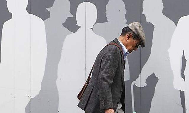 A man walks past an advertisement signboard at a shopping district in Tokyo