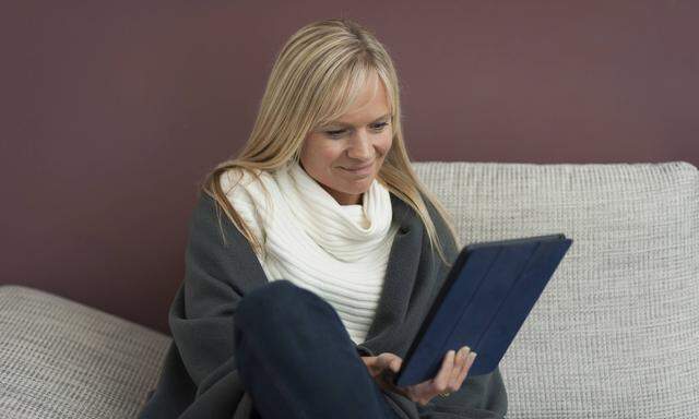 Woman sitting at home reading e book model released Symbolfoto property released PUBLICATIONxINxGER