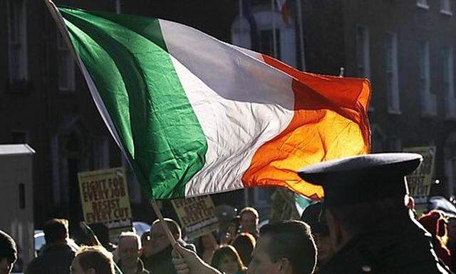 A protestor waves a tri-color flag outside Government Buildings