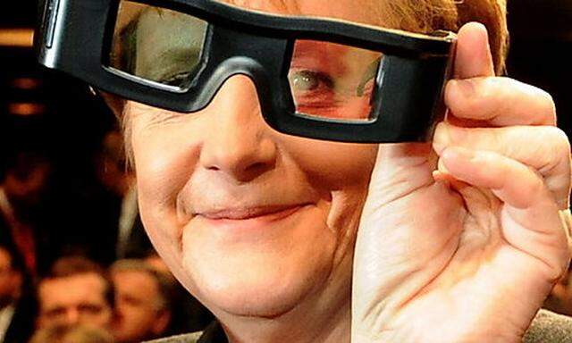 Merkel nimmt die neuen 3D-Brillen unter die Lupe