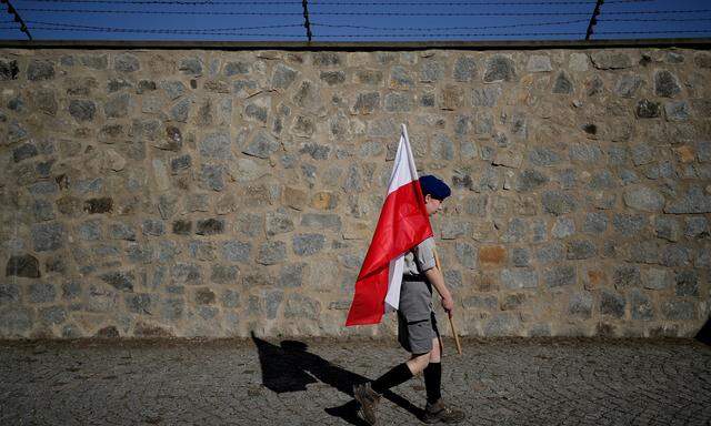 Ein Scout aus Polen trägt eine polnische Nationalflagge an der Gedenkstätte des ehemaligen Konzentrationslagers Mauthausen 