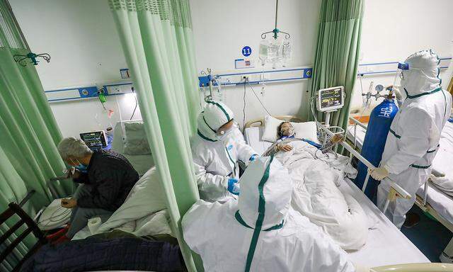 Medical workers in protective suits attend to a novel coronavirus patient at an isolated ward of a designated hospital in Wuhan